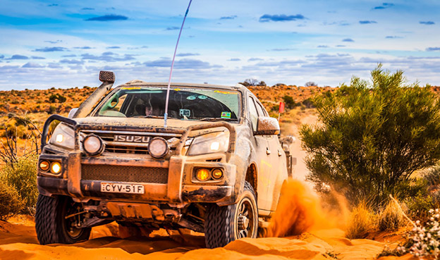 Isuzu Ute drives up sandy hill in outback
